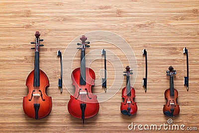 Set of four toy string musical orchestra instruments: violin, cello, contrabass, viola on a wooden background. Music concept. Stock Photo