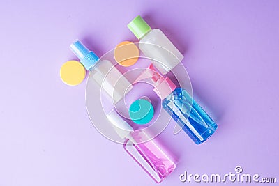 Colorful travel size bottles with cosmetics on lavender background. Stock Photo