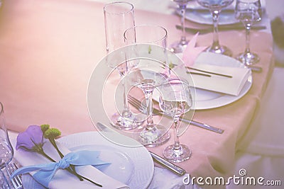 A set of glass of wedding setting with cutlery with a violet flower rose . Table for an event party or wedding reception. Stock Photo