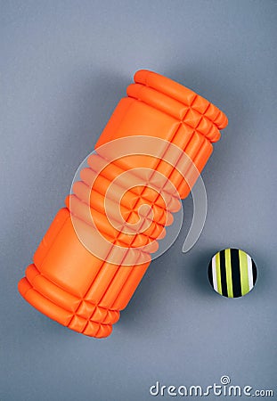 Set of green fascia release ball, orange bumpy foam massage roller for trigger points over grey background Stock Photo