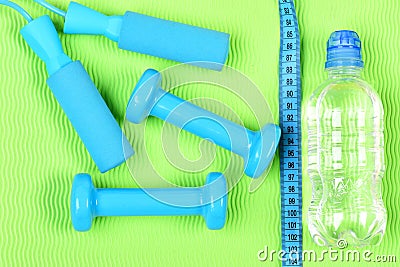 Set of hand weights and jump rope on bright background. Stock Photo