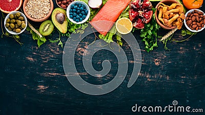 A set of healthy food. Fish, nuts, protein, berries, vegetables and fruits. On a black wooden background. Stock Photo