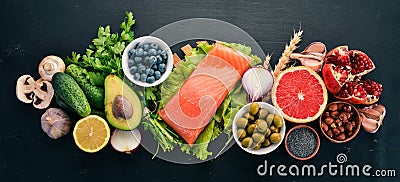 A set of healthy food. Fish, nuts, protein, berries, vegetables and fruits. On a black wooden background. Stock Photo