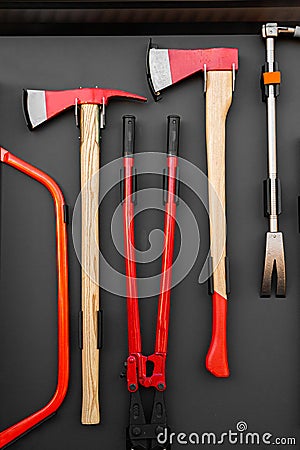 A set of sturdy axes, pliers and crowbars attached to stand in modern fire truck Stock Photo