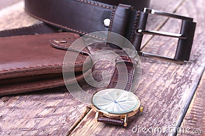 Set of men`s accessories for the business with leather belt, wallet, watch and smoking pipe on a wooden background. The Stock Photo