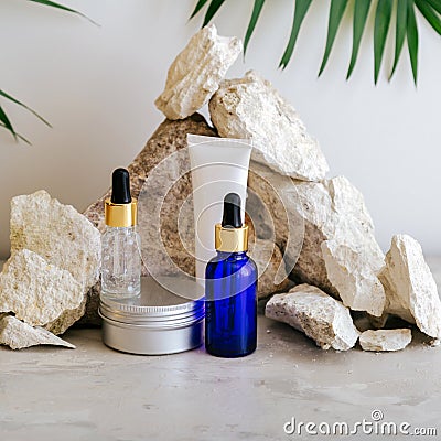 Set natural beauty cosmetic skincare products with palm leaf plant on stone pedestal, rock pile balancing stones gray Stock Photo