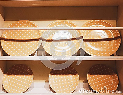 Set of orange polka-dotted plates on a wooden shelf Stock Photo