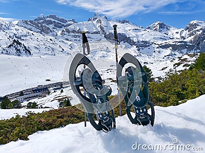set of a pair of snowshoes or rackets of snow and two ski poles on the cold white snow ready to walk on the snowy mountain in a Stock Photo