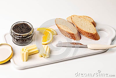 A set of premium black caviar, three pieces of white bread, butter on a serving platter. Stock Photo