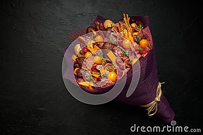 A set of products such as sausage, cheese, bread and tomatoes is packed in a stylish bouquet Stock Photo