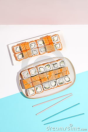 Set of salmon sushi rolls. Philadelphia maki in ceramic dishware on coloured backdrop. Sushi menu concept. Modern japanesse food. Stock Photo