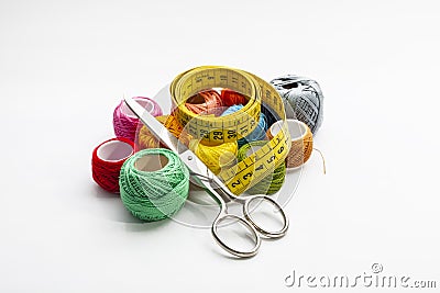 Set of several spools of thread of different colors, a pair of scissors and a tailors tape on a white background. Stock Photo