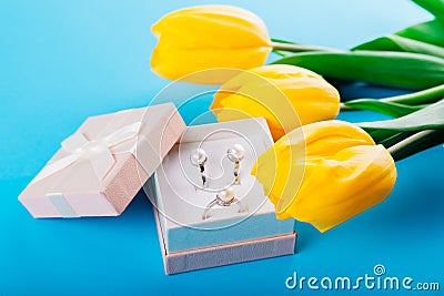 Set of silver ring and earrings with pearls in the gift box with yellow tulips. Present for a Mother`s Day Stock Photo