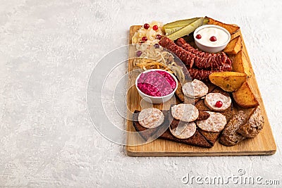 Set of snacks: sausages, toast, sauerkraut, marinated onion and cucumber, baked potato. Side view, copy space Stock Photo