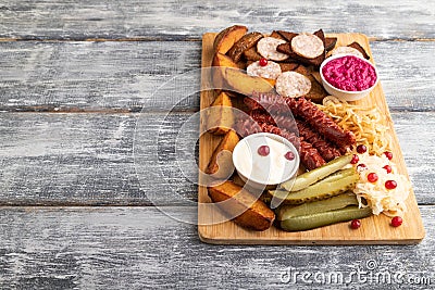 Set of snacks: sausages, toast, sauerkraut, marinated onion and cucumber, baked potato. Side view, copy space Stock Photo