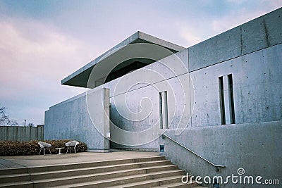 Set of stairs leading to the side of a modern cement building, with two simple chairs Stock Photo