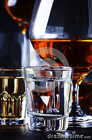 Set of strong alcoholic drinks in glasses and shot glass in assortent: vodka, rum, cognac, tequila, brandy and whiskey. Dark Stock Photo