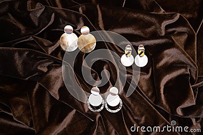 A set of stylish trendy earrings on crumpled brown fabric background. Fashionable women's costume jewelry for a party Stock Photo