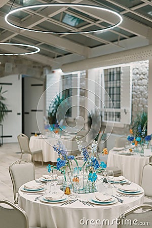 Set tables with bouquets of flowers in a restaurant with round lamps Stock Photo