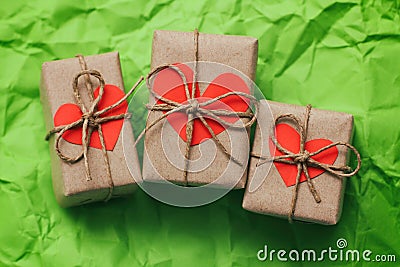Set of three gift boxes tied with a rope on green crumbled paper background. Carton hearts cards. Stock Photo