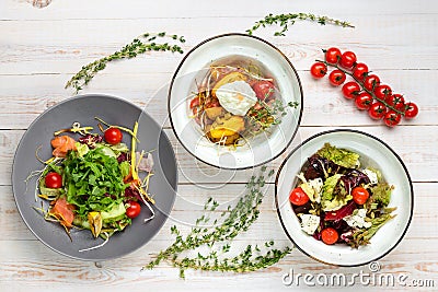 Set of three plates with vegetable salad. Healthy food for dieting. Lunch menu of food restaurant on white wooden background in Stock Photo