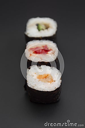 Set of three sushi rolls with fish, avocado and cheese on black background isolated. Traditional japanese food. Asian restaurant Stock Photo