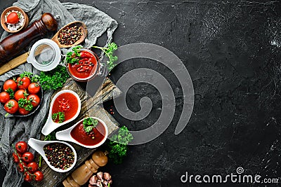 A set of tomato sauces on a black stone background. Ketchup, barbecue sauce, tomato sauce. Top view. Stock Photo