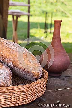 Set two rural bread in a wicker basket tray of clay jug narrow with butter milk on a table snack in the open air Stock Photo