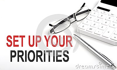 SET UP YOUR PRIORITIES Concept. Calculator,pen and glasses on white background Stock Photo