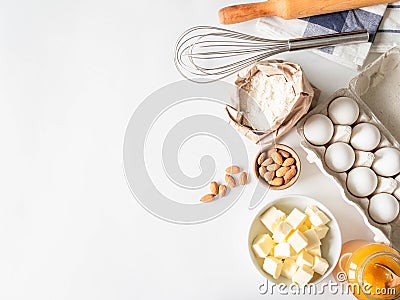 Set of various baking ingredients - flour, eggs, sugar, butter, honey, nuts and kitchen utensils on white background. Top view Stock Photo