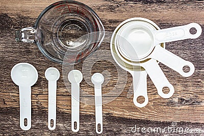 Set of white measuring cups, measuring spoons and measuring glass use in cooking lay on wooden tabletop in top view Stock Photo