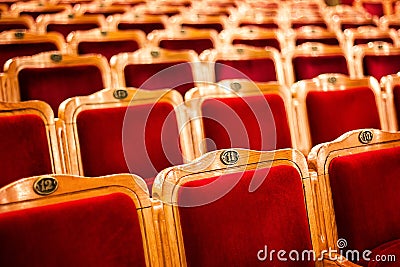 Sets on an empty theatre, taken with selective focus and shallow depth of field. Empty vintage red seats with numbers, teather cha Stock Photo