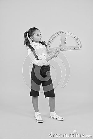 Setting square with protractor. Little girl using triangle to measure angles in degrees on yellow background. Small Stock Photo