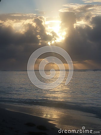 The setting sun, hidden in the cloud, reflects in the sea Stock Photo