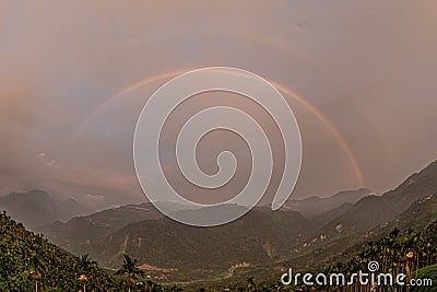 The setting sun and the sky appear Primary and Secondary Rainbow Stock Photo