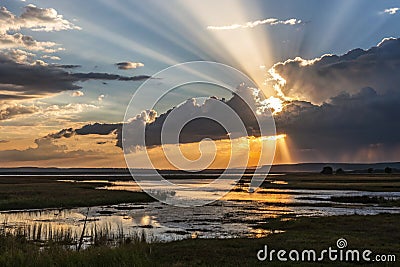 a setting sun wuth crepuscular rays setting over wet landscape- generated using ai Stock Photo