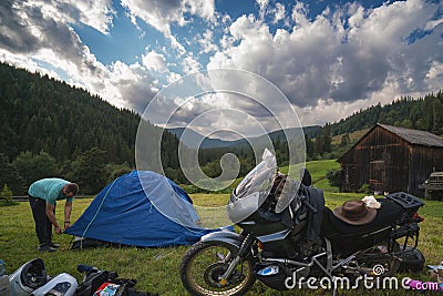 Setting up a blue tent with a great view of the mountains. A trip on a motorbike. A touring motorcycle with lots of gear. Bags, Stock Photo