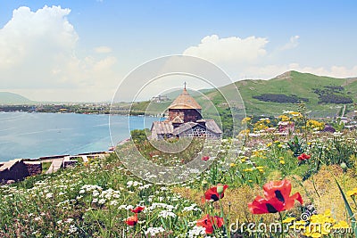 Sevanavank is sightseeing in Armenia. View of Lake Sevan, green mountains and sky. Blooming field with yellow and white flowers. Stock Photo