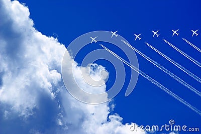 seven aeroplanes with contrails flying high in the blue sky Stock Photo