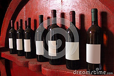 Seven bottles of wine with their own shadow resting on a wooden Stock Photo