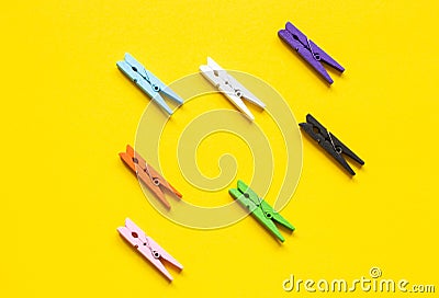 Seven colored clothespins in a row on a yellow background Stock Photo