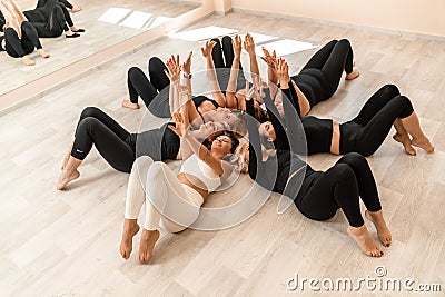 Seven happy women lie on their backs on the floor with their heads pressed together. Stock Photo