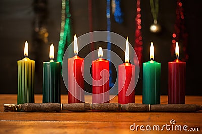 seven kwanzaa candles, unlit, arranged in a row on wooden surface Stock Photo