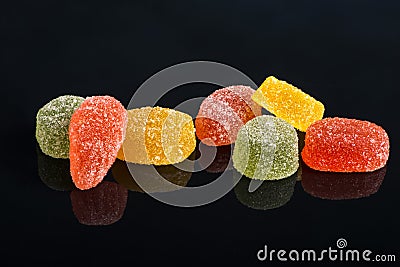 Seven multi-colored fruit-paste sweets on the black reflecting Stock Photo