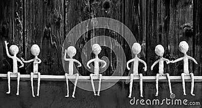 Seven white figures sitting on a wooden shelf in various poses Stock Photo