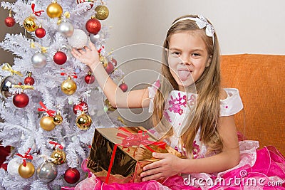 Seven-year girl in beautiful dress sits with a gift and showed language to frame Stock Photo