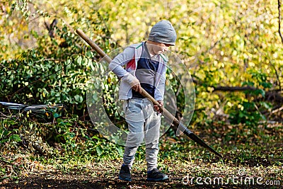Seven year old boy with big shovel in the garden Stock Photo