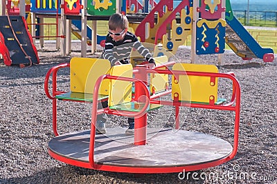 Seven-year-old boy spinning on the carousel on the Playground. Stock Photo