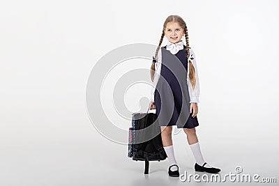 A seven year old school girl in a school uniform poses on a white or light background Stock Photo