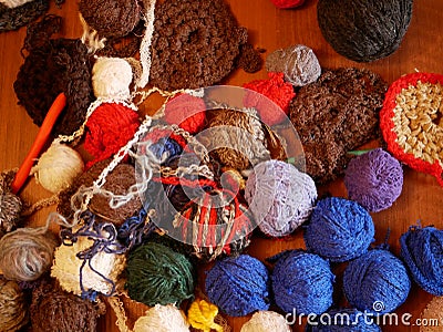 Several balls of multicolored woolen threads lie on a wooden table. The yarn is prepared for needlework. Stock Photo